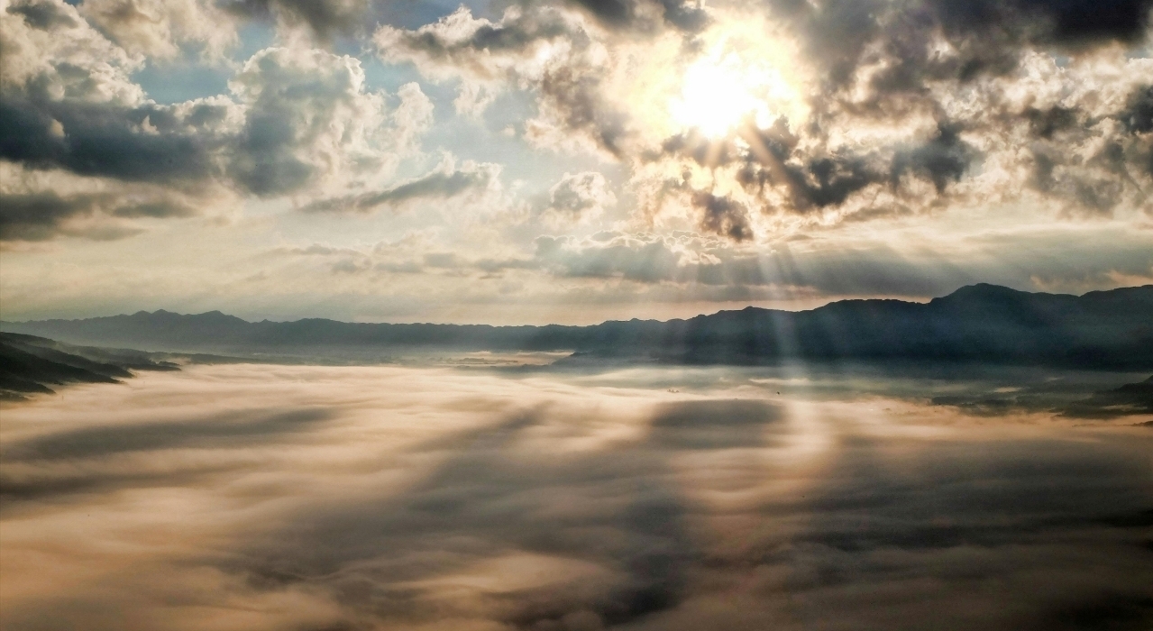 Sunny image of lake covered in mist in front of mountains